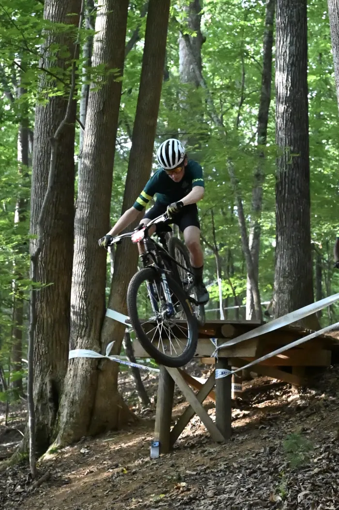 Rider rolling off a wooden drop in the forest